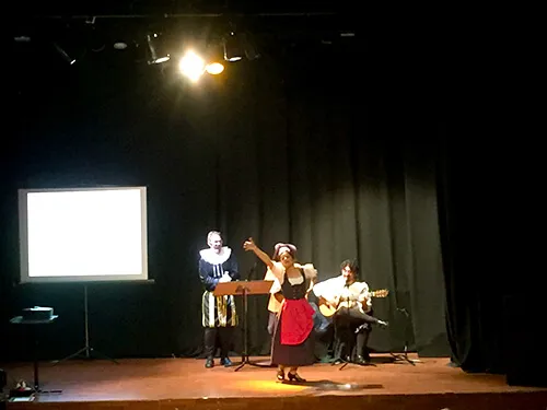 Actuación musical en un escenario con pantalla de proyección al fondo