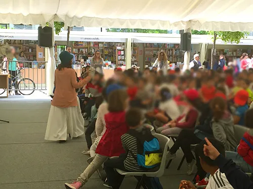 Feria del libro bajo carpa, con casetas de librerías y público asistiendo