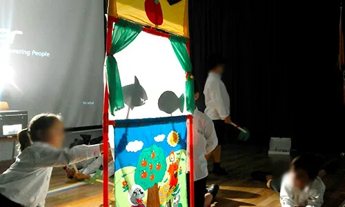 Niños tras un teatrillo de sombras con decorado pintado a mano
